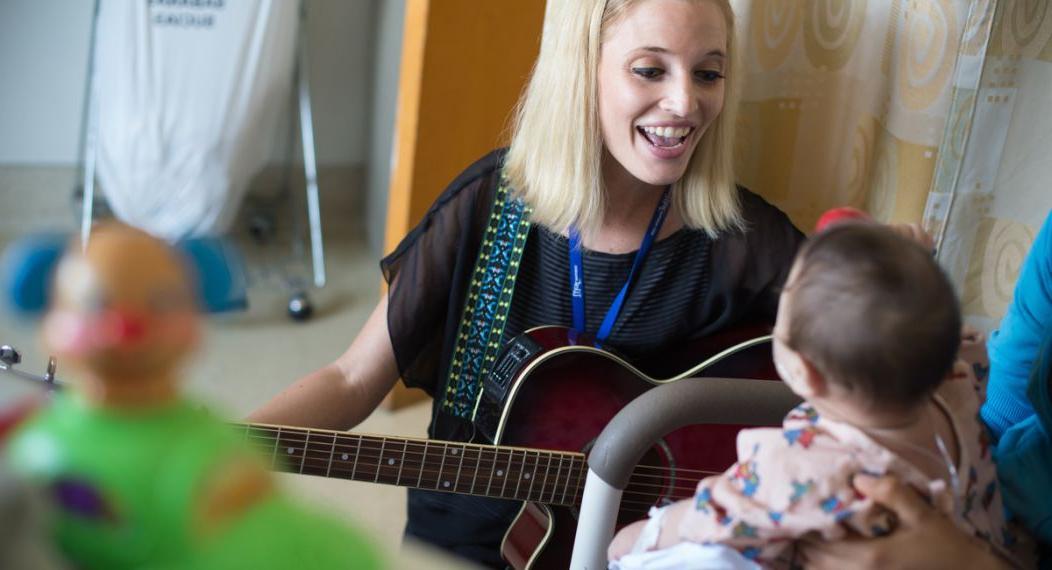 正规博彩十大网站 MA in Music Therapy student Kathleen Humphries works with young patient during field visit.